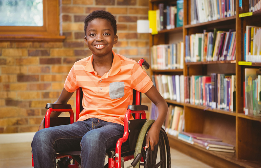 Image of of a young boy seated in a wheelchair inside a library