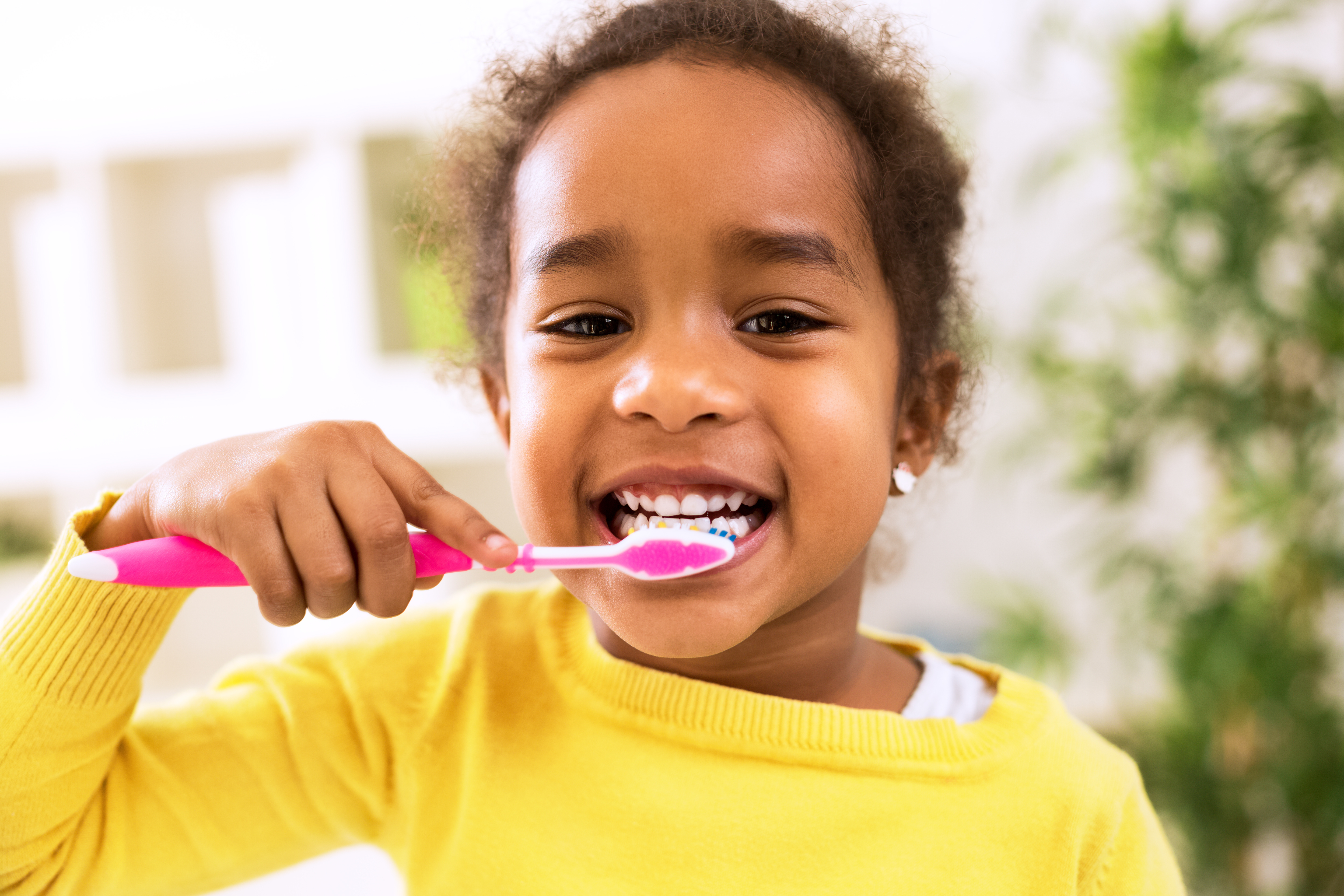 Child smiling and brushing their teeth